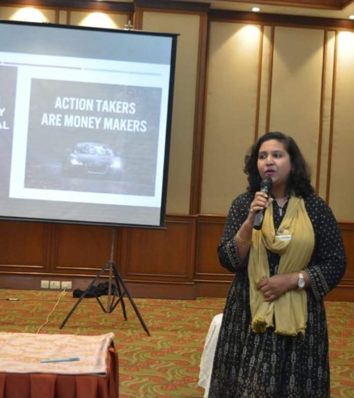 Speaking beside a slide reading Action takers are money makers